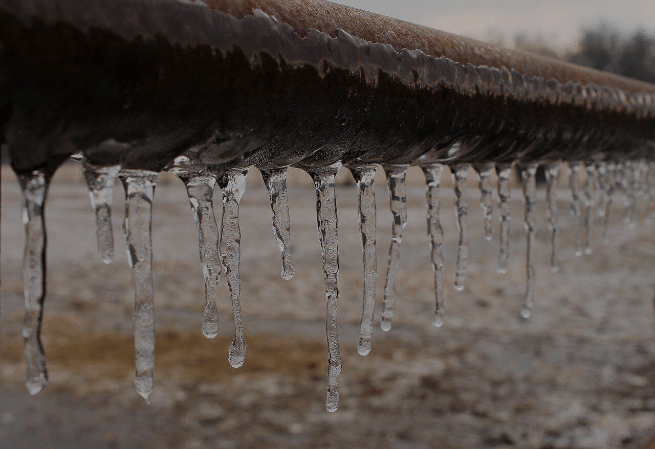 Icicles hanging from a frozen pipe in winter