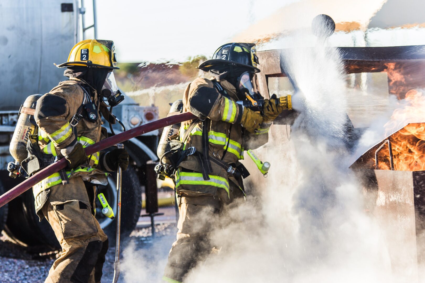 A fireman in full gear is spraying water from the hose.